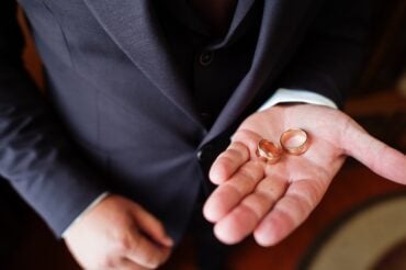 groom holding wedding bands